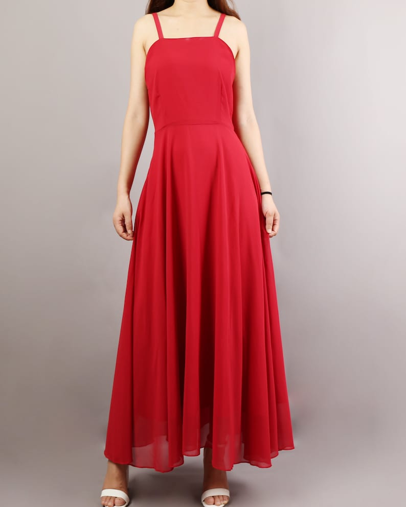 K&ouml;nnte beinhalten: Ein langes, rotes, &auml;rmelloses Maxikleid mit quadratischem Ausschnitt und d&uuml;nnen Tr&auml;gern. Das Kleid hat eine flie&szlig;ende, A-f&ouml;rmige Silhouette.