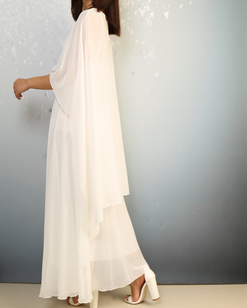 K&ouml;nnte beinhalten: Ein wei&szlig;es, flie&szlig;endes Maxikleid mit einem drapierten, asymmetrischen Design. Das Kleid ist aus einem leichten, durchsichtigen Stoff gefertigt und hat eine lockere Passform.