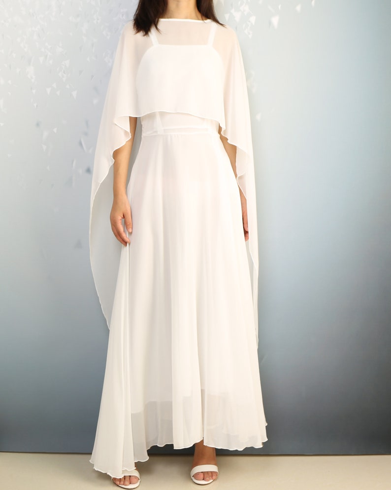 K&ouml;nnte beinhalten: Ein wei&szlig;es Maxikleid mit einem durchsichtigen Umhang dar&uuml;ber. Das Kleid hat ein schlichtes, elegantes Design und ist perfekt f&uuml;r einen besonderen Anlass.