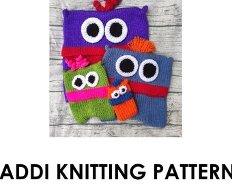 May include: Four knitted monster pockets in different colours and designs. The pockets are made with a variety of colours, including purple, blue, green, and orange. Each pocket has a unique face with eyes, a mouth, and other details. The pockets are arranged in a stack on a wooden surface. ADDI KNITTING PATTERN MONSTER POCKETS