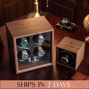 May include: A wooden watch winder box for four watches with a glass front, engraved with "Javier" and "May 26, 2024," alongside a single wooden watch winder box engraved with "E" and "Eason." Both feature dark wood grain and black interiors.