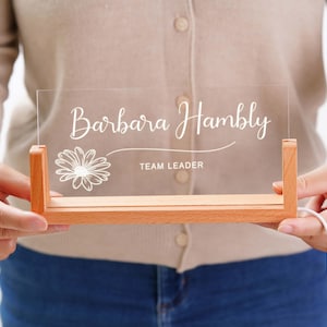 a person holding a clear acrylic sign with a flower on it