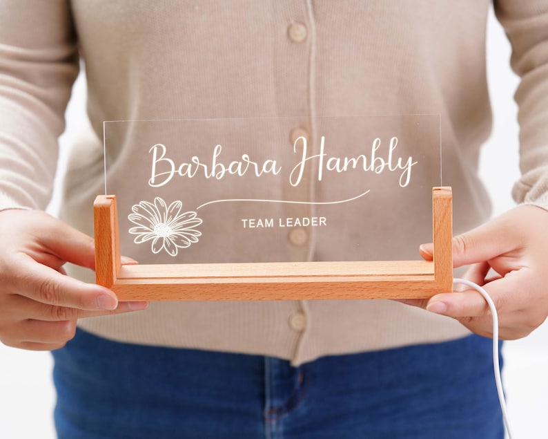 a person holding a clear acrylic sign with a flower on it