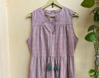 May include: A sleeveless tiered maxi dress with a red and white striped pattern. The dress has a V-neckline with a tie detail and green tassels.