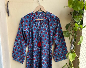 May include: A long blue cotton dress with a red floral print. The dress has a V-neckline and a tie at the neckline with a tassel. The sleeves are long and the dress has a gathered skirt.