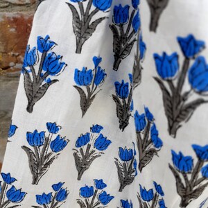 May include: White fabric with a repeating pattern of blue and gray stylized tulips.
