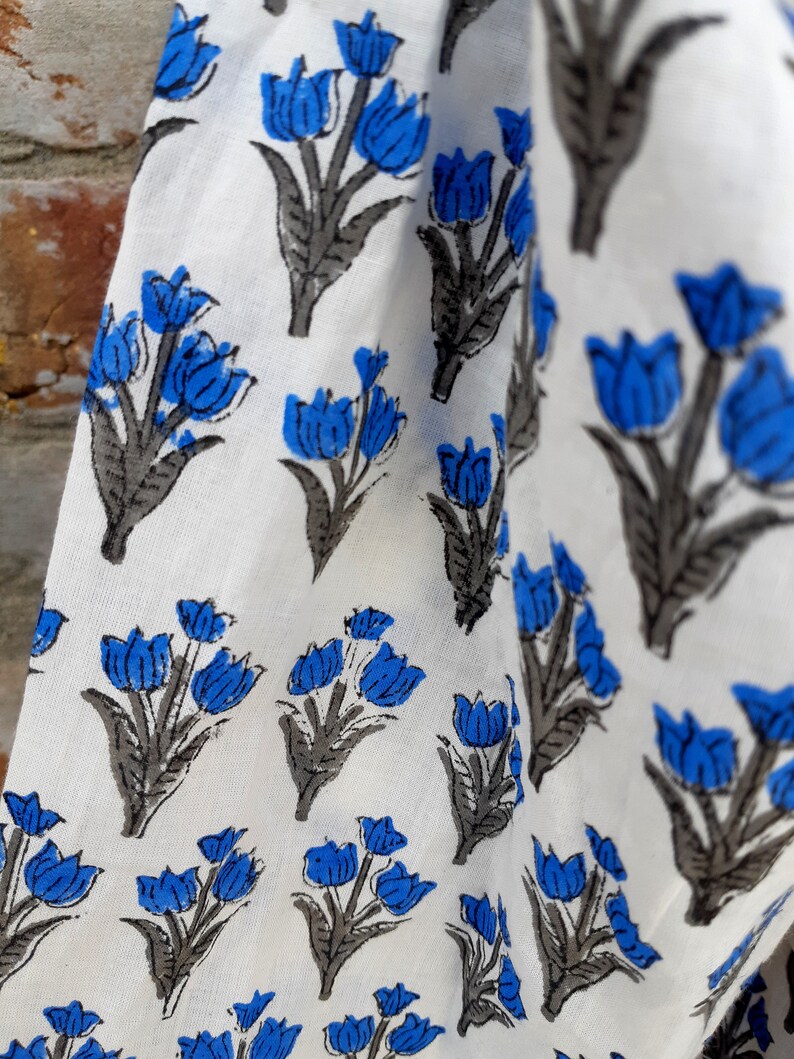 May include: White fabric with a repeating pattern of blue and gray stylized tulips.