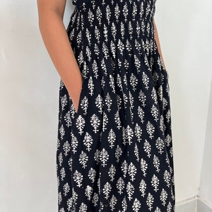 May include: A black maxi dress with a white floral print. The dress has a smocked waist and short sleeves.