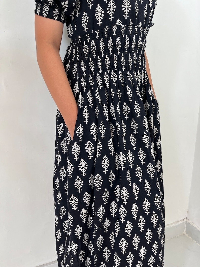 May include: A black maxi dress with a white floral print. The dress has a smocked waist and short sleeves.