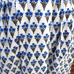 May include: White fabric with a blue and gray floral print. The fabric has a pleated design.
