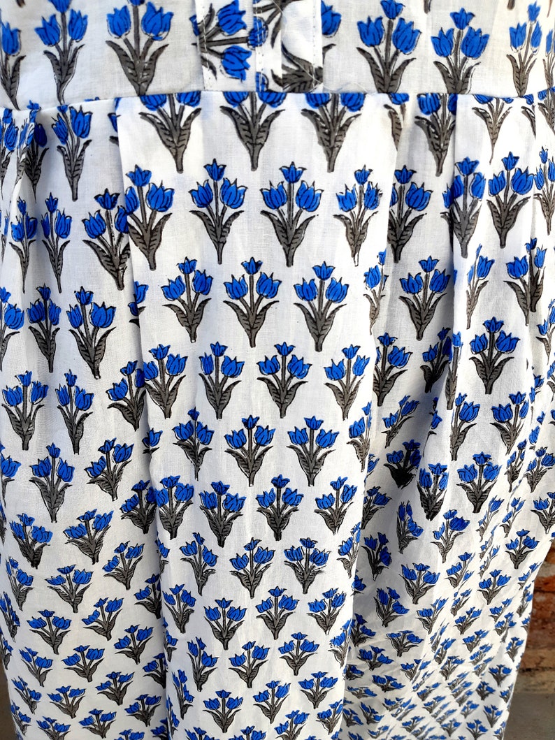 May include: White fabric with a blue and gray floral print. The fabric has a pleated design.