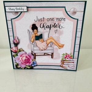 May include: A pink and green birthday card featuring a woman sitting in a chair reading a book. The card has the text "...Happy Birthday..." and "Just one more chapter..." on it.