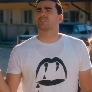 Op de afbeelding: Een wit T-shirt met een zwarte afbeelding van een mond met tanden en druppelende harten.
