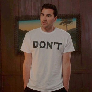May include: A man wearing a white t-shirt with the word "DON'T" printed in black letters.