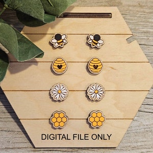 May include: Six pairs of wooden earrings with a bee, honeycomb, and daisy design. The earrings are displayed on a hexagonal wooden board.