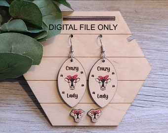 May include: A pair of wooden earrings with a cow design and the text "Crazy Lady". The earrings are oval shaped and have silver hooks. There are also two smaller cow-shaped earrings.