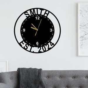 May include: Black metal wall clock with white numbers and a gold clock hand. The clock face is surrounded by a black circle with the text "SMITH EST. 2024".