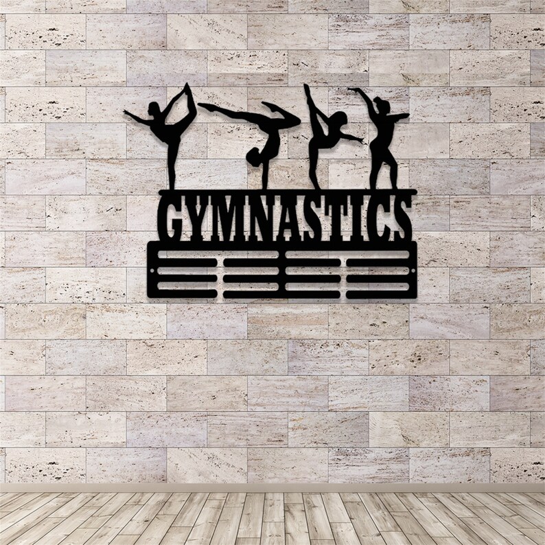 May include: Black metal gymnastics medal display with five gymnast silhouettes and the word "GYMNASTICS" above a row of 10 medal hooks.