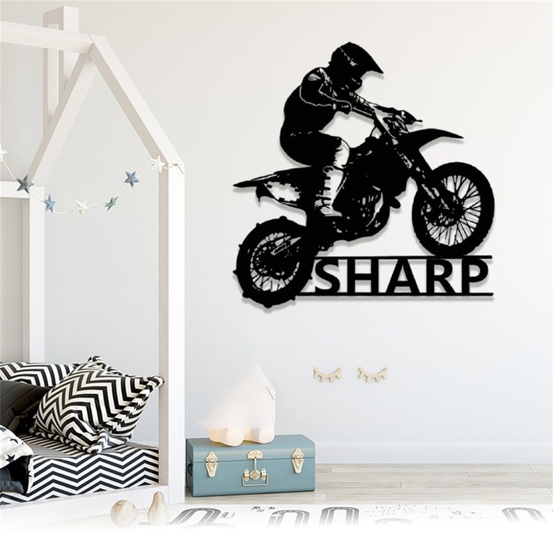 Op de afbeelding: Zwarte silhouet van een motorcrosser die met een crossmotor springt met de naam "SHARP" eronder.