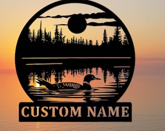 May include: Black metal wall art featuring a loon swimming on a lake at sunset. The design includes a silhouette of trees, a sun, and the text "CUSTOM NAME" at the bottom. The artwork is circular.