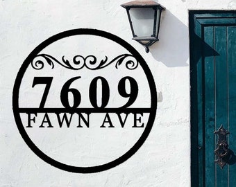 Puede incluir: Placa de número de casa de metal negro con un marco circular y adornos de desplazamiento. La placa muestra el número 7609 y el nombre de la calle "FAWN AVE".