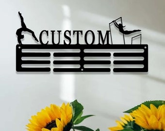 May include: Black metal medal display rack with the word "CUSTOM" in large letters. The rack has 8 slots for medals and features a gymnast silhouette on each end.