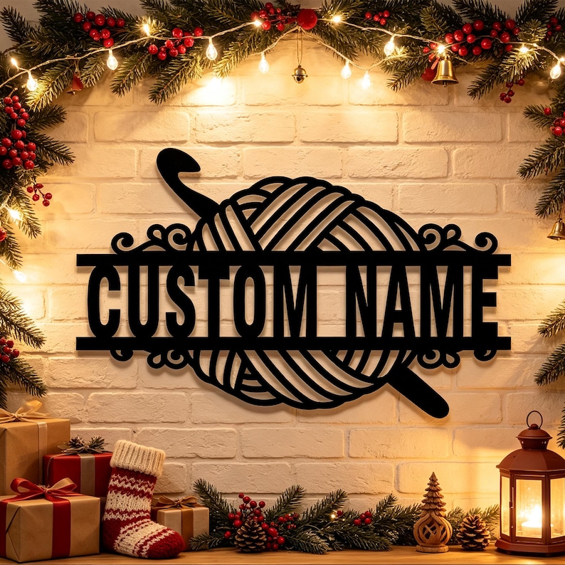 Pode incluir: Uma placa de parede em metal preto com um novelo de l&atilde; e uma agulha de croch&ecirc; inserida. Uma barra horizontal atravessa o centro do novelo, exibindo o texto CUSTOM NAME em letras mai&uacute;sculas em negrito e sem serifa.