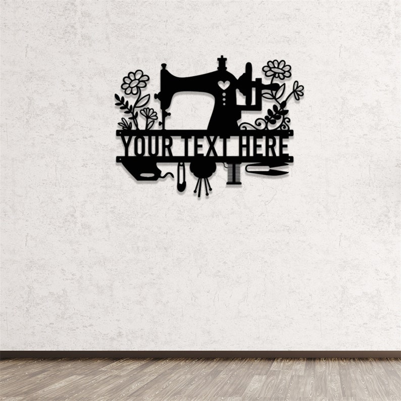May include: Black metal wall art featuring a sewing machine design with floral accents. The text "YOUR TEXT HERE" is displayed prominently. Includes depictions of sewing tools like a needle, thread, and scissors. Ideal for a craft room or sewing enthusiast.