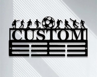 May include: Black metal medal display with a soccer ball and players silhouette design. The display has the word "CUSTOM" at the top and 10 rows of medal hooks.
