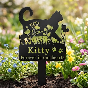 Könnte beinhalten: Schwarzer Metall-Gartenstecker mit einer Katzen-Silhouette und floralen Details. Der Stecker trägt die gelbe Aufschrift "Kitty Forever in our hearts" mit Pfotenabdrücken. Der Stecker befindet sich in einem Blumengarten.