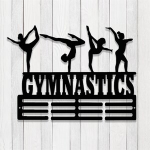 May include: Black metal gymnastics medal holder with four gymnast silhouettes and the word "GYMNASTICS" above a row of medal hooks.