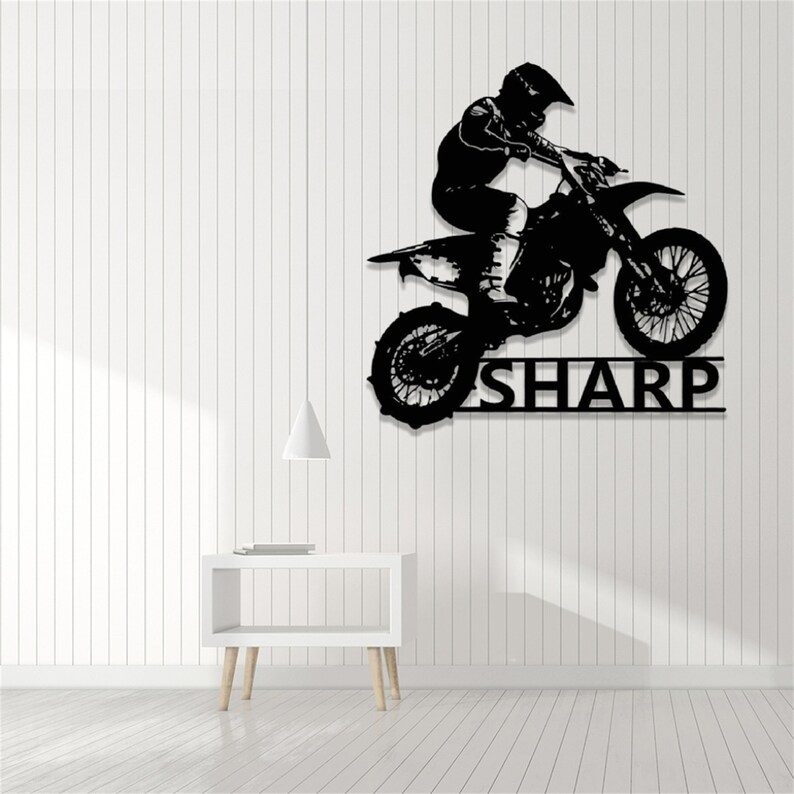 Op de afbeelding: Zwarte silhouet van een motorcrosser die springt op een crossmotor met de naam "SHARP" eronder.