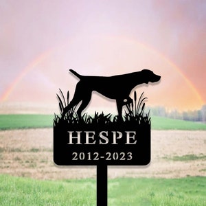 Può includere: Silhouette nera di un Bracco tedesco a pelo corto in piedi nell'erba alta con un cartello in metallo nero che recita "HESPE 2012-2023".