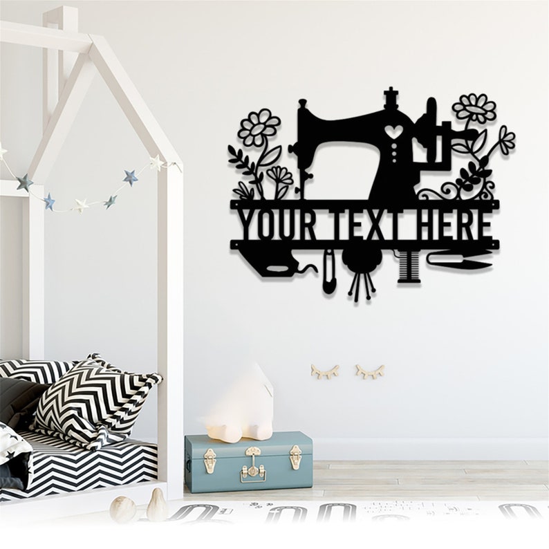 May include: Black metal wall art featuring a sewing machine design with floral accents. The design includes the text "YOUR TEXT HERE" and various sewing tools. A decorative piece for a craft room or sewing enthusiast.