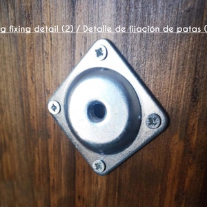 May include: Close-up of a silver metal leg fixing detail with four screws. The detail is mounted on a dark brown wooden surface.