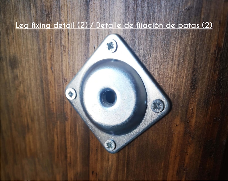 May include: Close-up of a silver metal leg fixing detail with four screws. The detail is mounted on a dark brown wooden surface.