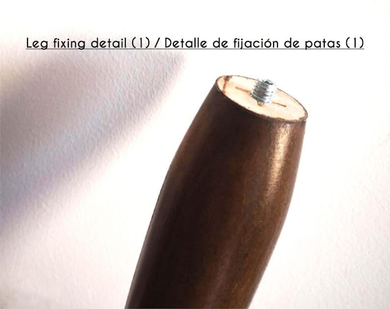 May include: Close-up of a wooden furniture leg with a metal screw. The screw is inserted into a hole in the top of the leg. The leg is brown and has a smooth finish.