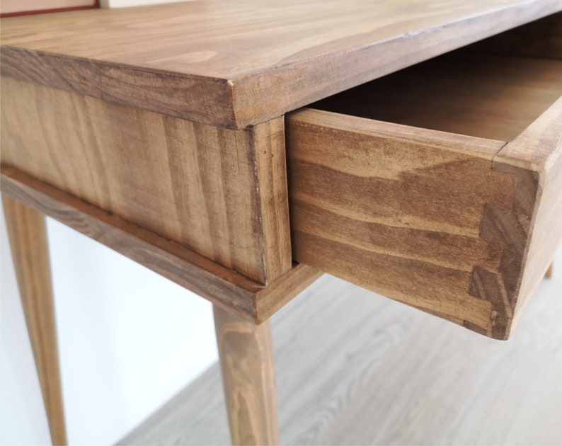 May include: A wooden side table with a single drawer that is open. The table has a light brown stain and four legs.