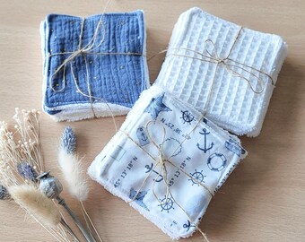 May include: Three sets of reusable makeup remover pads. One set is blue with gold flecks, one is white with a waffle texture, and one is white with a nautical print and the text "45° 13' 18" N" and "N 52.86° E".