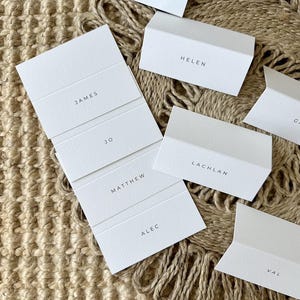 Moderne witte kaart gevouwen aangepaste plaatsnamen, klassieke gevouwen plaatsnamen bruiloft, eenvoudige gevouwen plaatsnamen, plaatsnamen evenement, tafelnaam