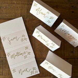 Handgeschreven moderne kalligrafie naamplaatje, kerstplaatsnaam, gouden ster plaatsnaam, tafelnaam, gepersonaliseerde tafelnamen, aangepaste naamkaart