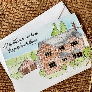 May include: A watercolor illustration of a brick house with a garage. The house has a brown roof, white windows, and a green lawn. The text "Welcome to your new home, Nearbrook House" is written in cursive on the card.