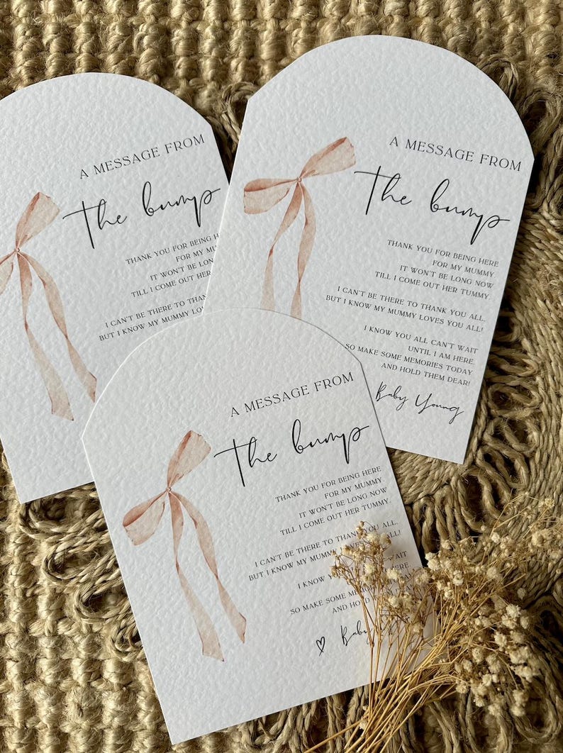 May include: Three white cards with a watercolor illustration of a pink bow. The cards have the text "A message from the bump" and a message from the baby to the guests.
