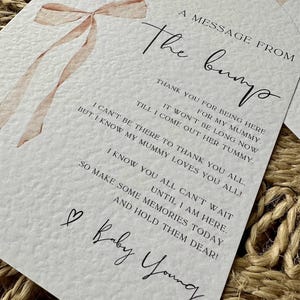 May include: A white card with a pink ribbon illustration and the text "A message from the bump". The card includes a message from the bump to the mother thanking her for being there and expressing excitement for the baby's arrival. The card is signed "Baby Young".