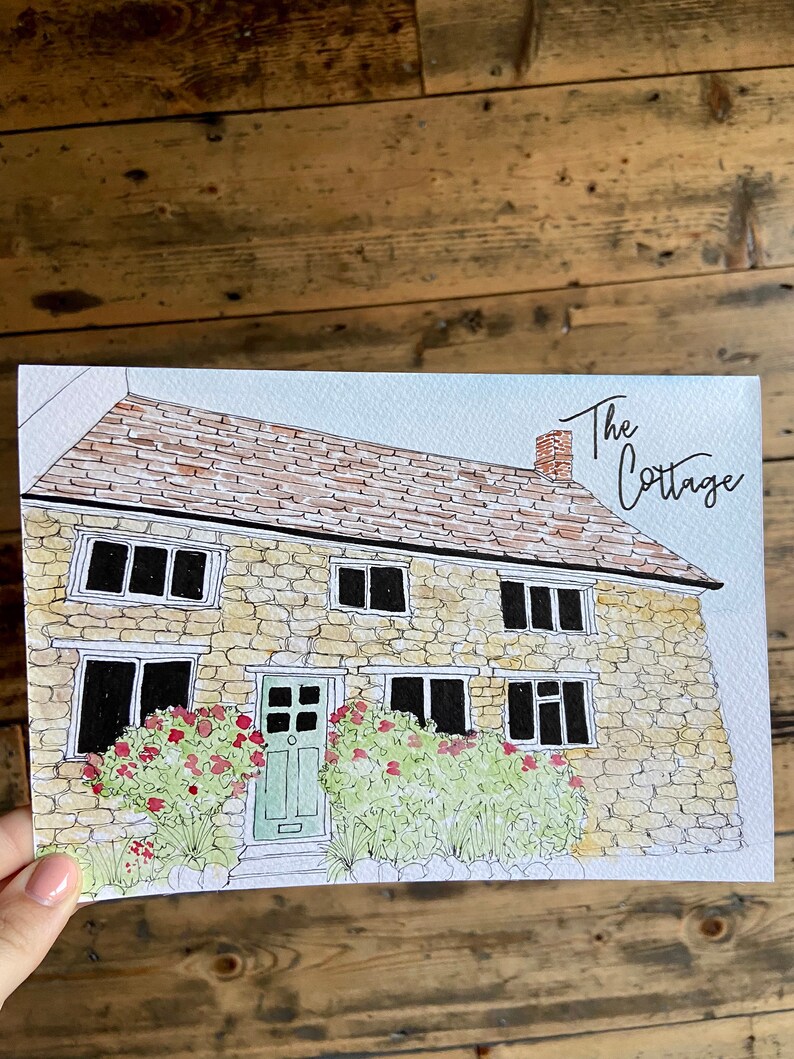 May include: Watercolor illustration of a stone cottage with a green door and red flowers. The text "The Cottage" is written in cursive above the house.
