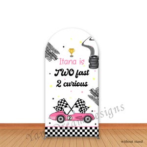 May include: A white backdrop with a pink race car, checkered flags, and tire tracks. The text "Itana is TWO fast 2 curious" is displayed in pink and black. A gold trophy and stars complete the design.