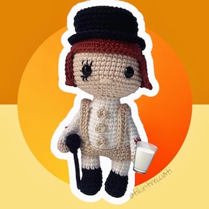 Peut inclure: Une poupée en crochet portant un chapeau haut de forme noir, une chemise blanche à boutons et un pantalon marron. La poupée tient un verre de lait et un bâton noir. La poupée a les cheveux bruns et un visage blanc avec des yeux noirs.
