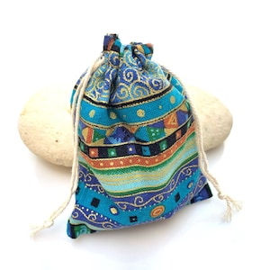 May include: A small blue and gold drawstring bag with a geometric pattern. The bag is made of fabric and has a white drawstring.