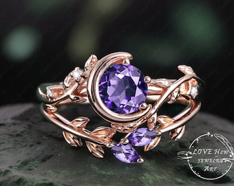 May include: A rose gold ring with a crescent moon design and a large purple amethyst gemstone. The ring is set with smaller amethyst gemstones and diamonds on the band.