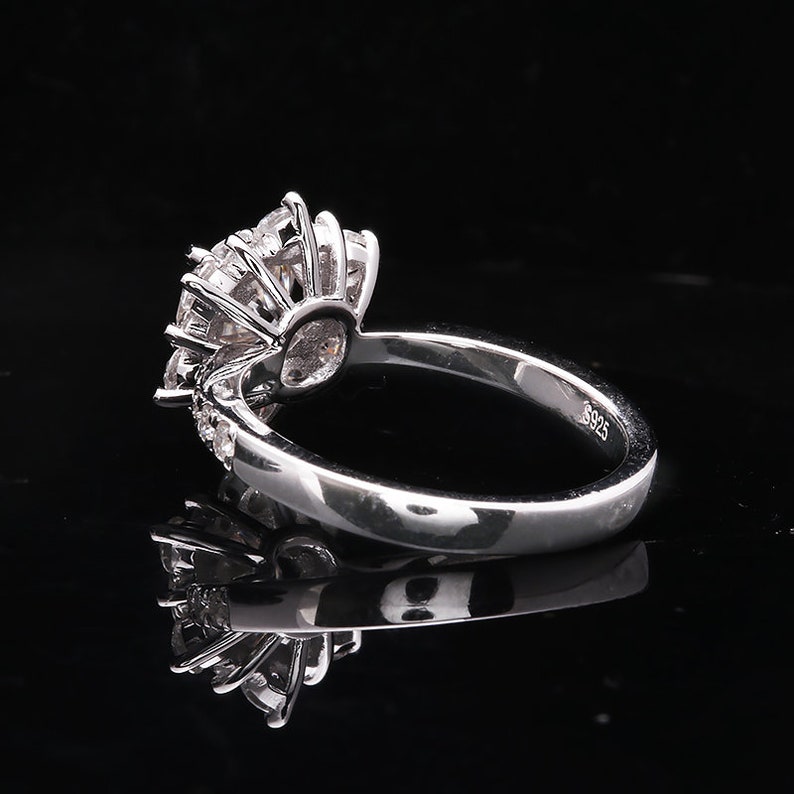 May include: A silver ring with a large, round, clear stone surrounded by smaller clear stones. The ring is marked with "925" on the inside of the band.